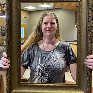 smiling woman holding an antique picture framing her face.