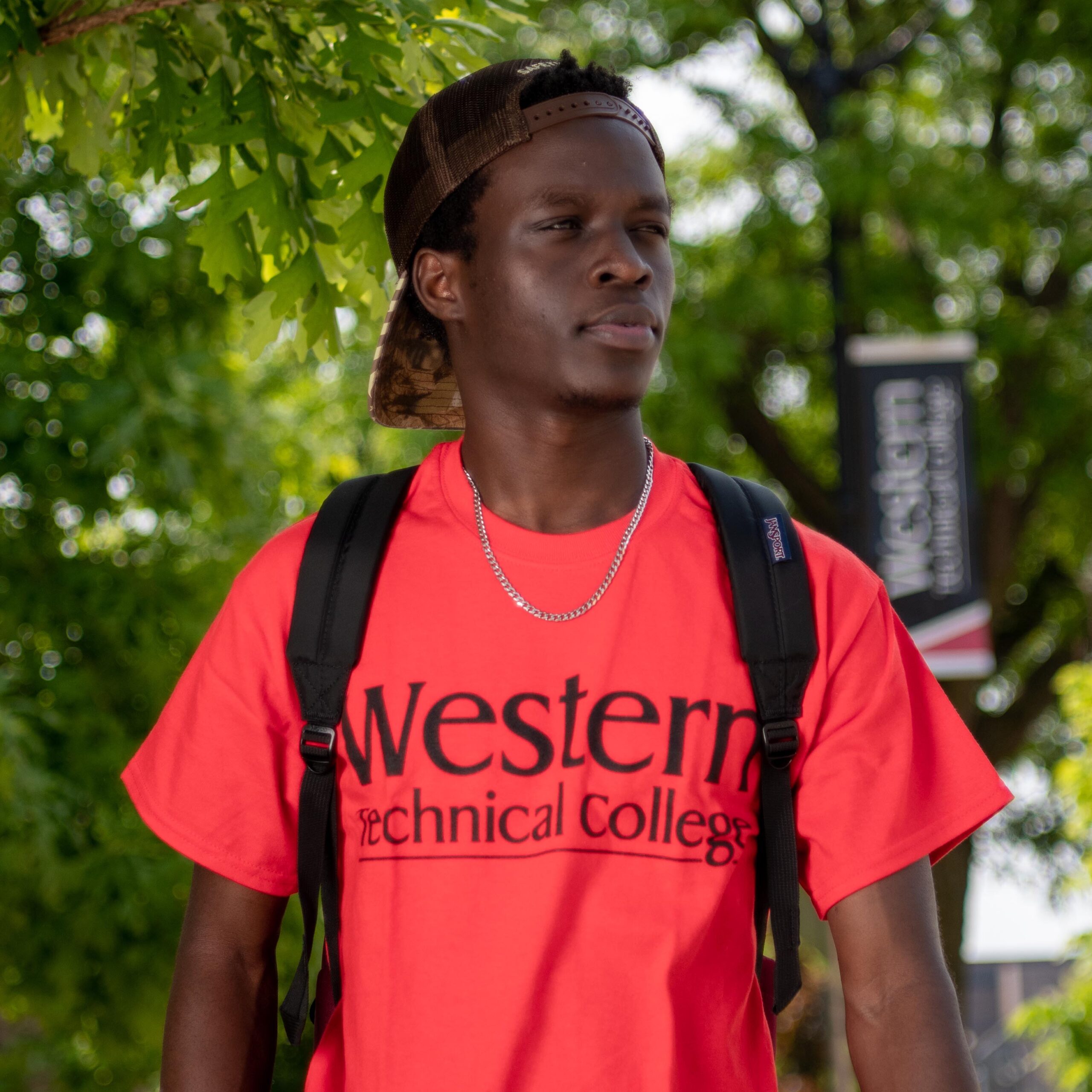 man walking with red shirt and backpack